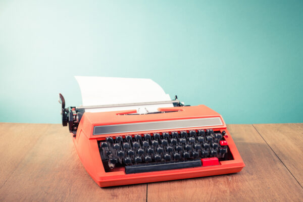 Retro old typewriter with paper on wooden table front mint green background. Vintage style filtered photo